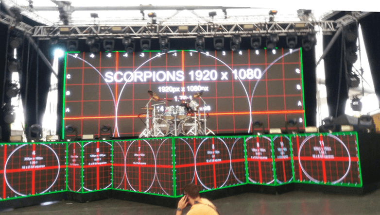 Stage screens displaying alignment grids behind and in front of a drum kit.