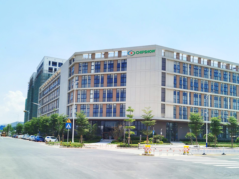 Multi-story industrial building with Chipshow signage beside a road.