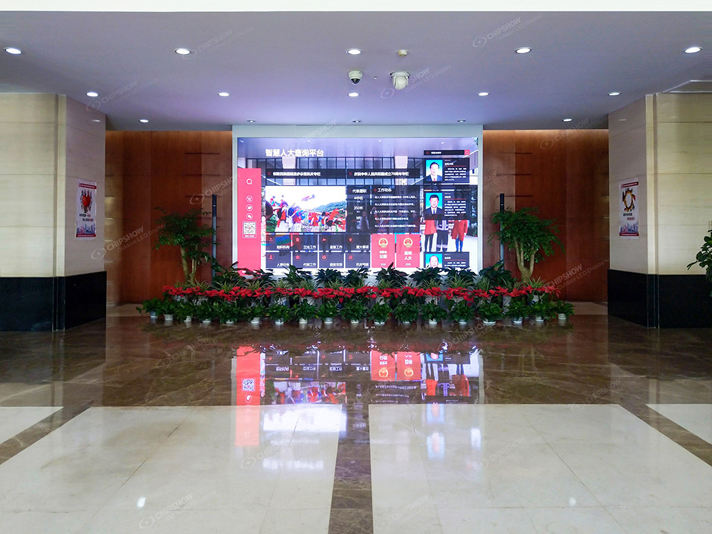 Lobby screen showing a multi-section information page above a row of plants.