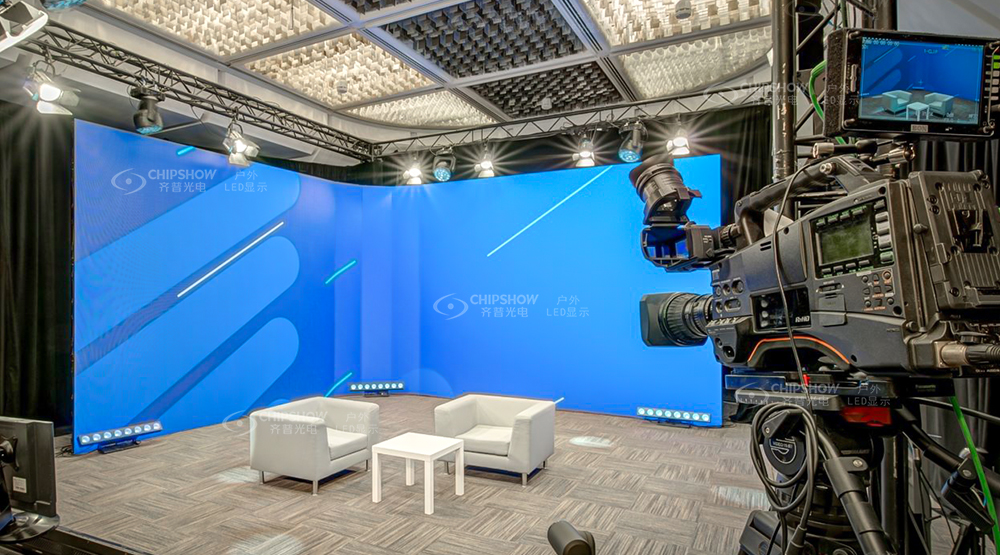 LED video wall studio with camera setup, white chairs, and curved blue display backdrop