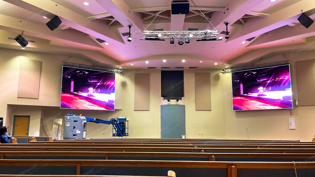 Modern church sanctuary with two large LED video screens on the side walls under purple lighting