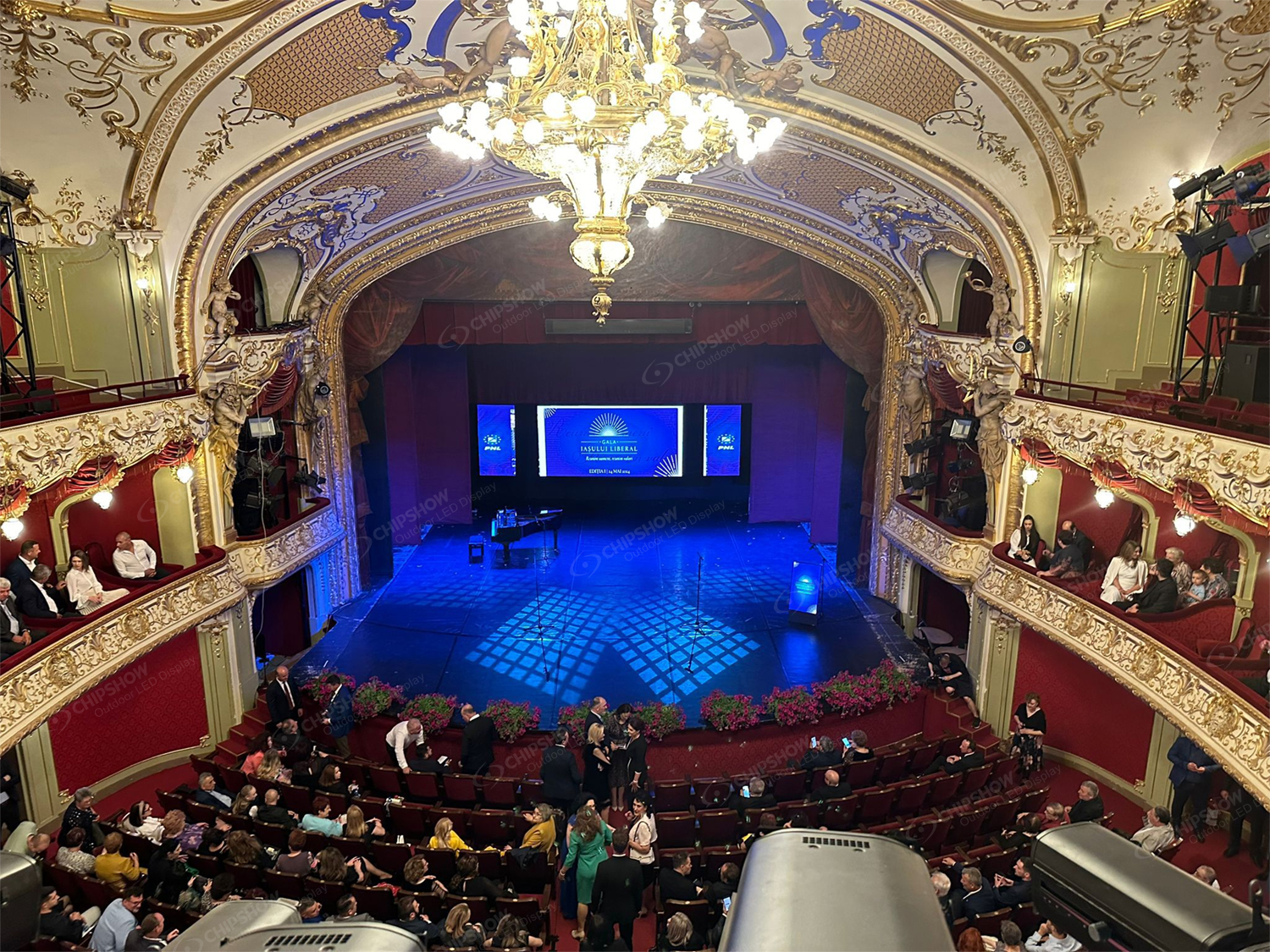 People standing on a stage in front of a central, brightly lit LED backdrop screen.