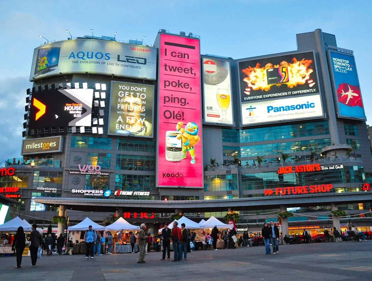 Large digital LED billboards on a commercial building facade in a busy urban square